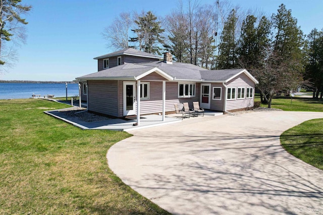 536 N W Gulliver Lake Rd, Gulliver, MI 49840 - view of front facade with a water view, a front lawn, a chimney, and a patio