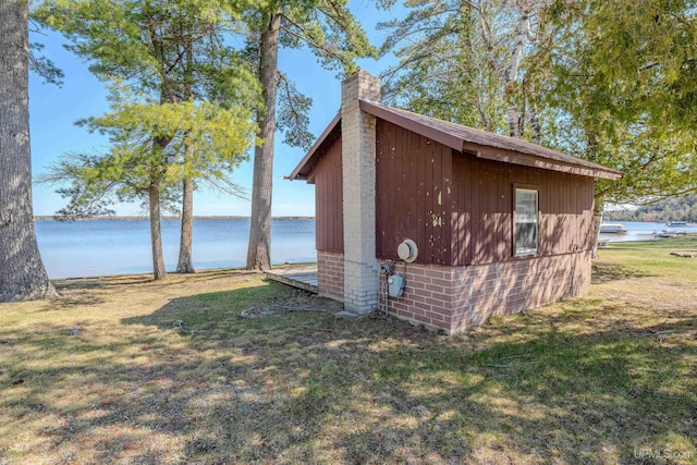 536 N W Gulliver Lake Rd, Gulliver, MI 49840 - view of side of home featuring a chimney, a lawn, a water view, brick siding, and an outbuilding