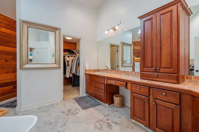 full bath with vanity, a spacious closet, marble look tile flooring, and a freestanding bath