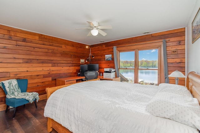 bedroom with wooden walls, dark wood-style floors, and ceiling fan