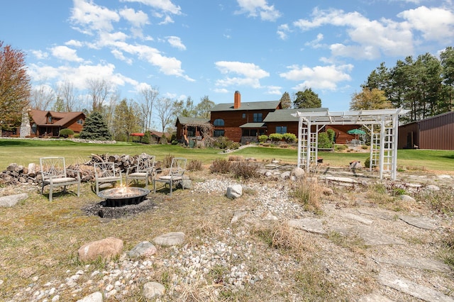 view of green lawn with a fire pit and a pergola