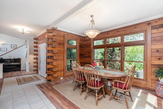 dining space with ornamental molding, wooden walls, and light wood finished floors