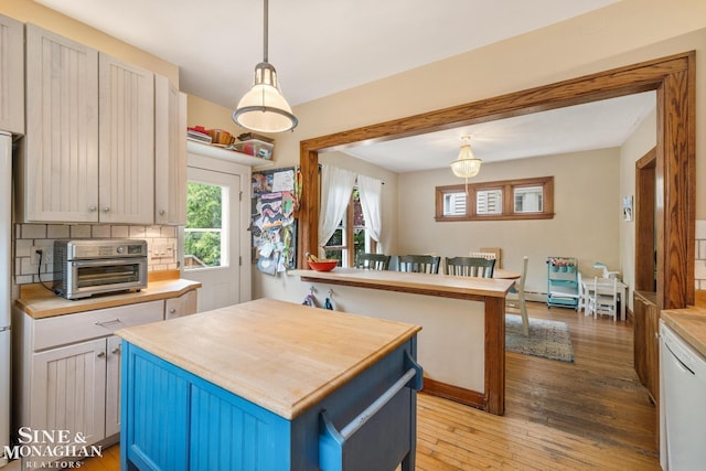 1117 Lakepointe St, Grosse Pointe Park, MI 48230 - kitchen featuring wood counters, white dishwasher, light wood-type flooring, a center island, and backsplash