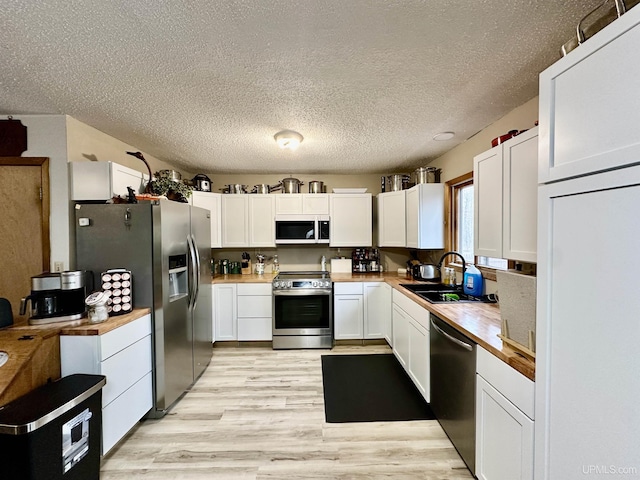 39 Stonegate Hts, Marquette, MI 49855 - kitchen with stainless steel appliances, a sink, butcher block counters, white cabinetry, and a textured ceiling