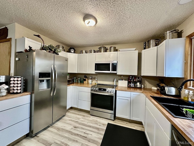 39 Stonegate Hts, Marquette, MI 49855 - kitchen featuring appliances with stainless steel finishes, wooden counters, a textured ceiling, white cabinetry, and light wood finished floors