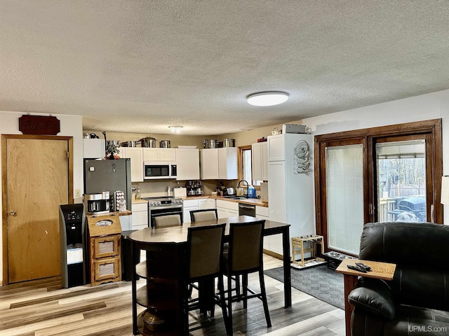 39 Stonegate Hts, Marquette, MI 49855 - kitchen with stainless steel appliances, white cabinets, a sink, light wood-style flooring, and a textured ceiling
