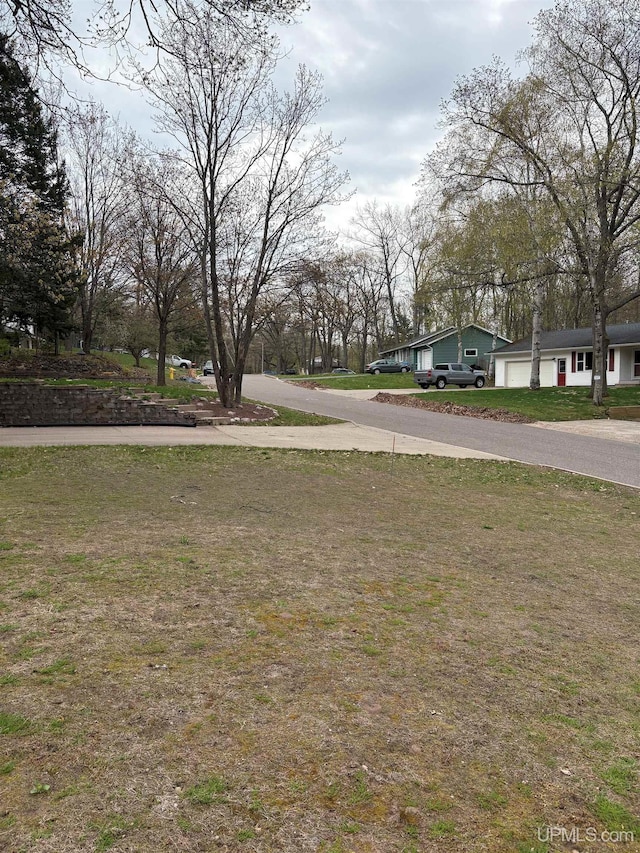 303 Jonathon Carver Rd, Marquette, MI 49855 - view of green lawn featuring driveway and an attached garage