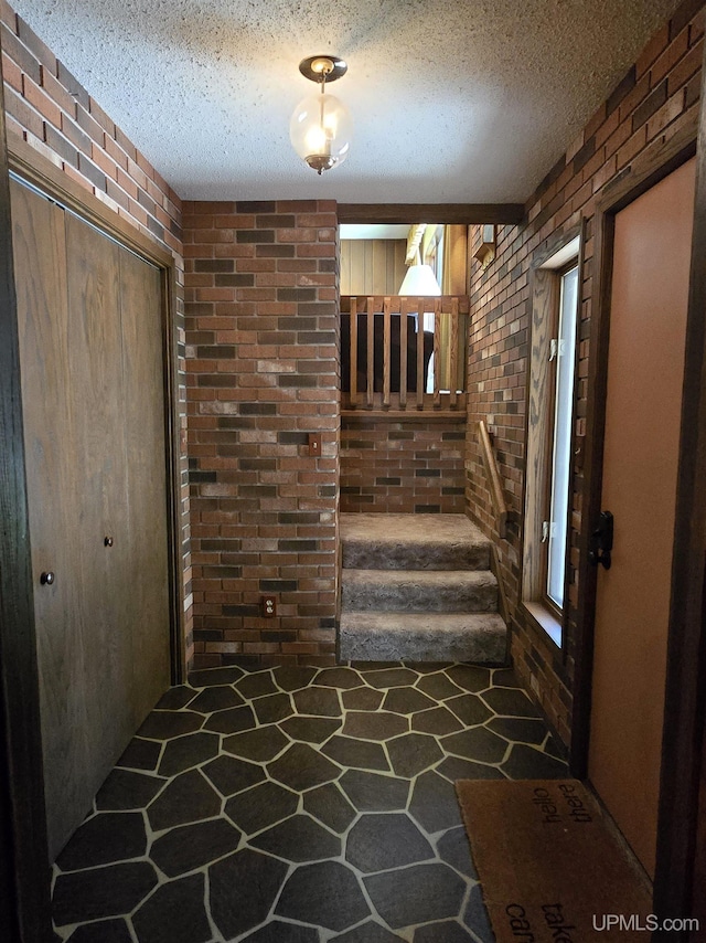 1604 Mildred Ave, Marquette, MI 49855 - entryway featuring brick wall, a textured ceiling, stairs, and stone floors