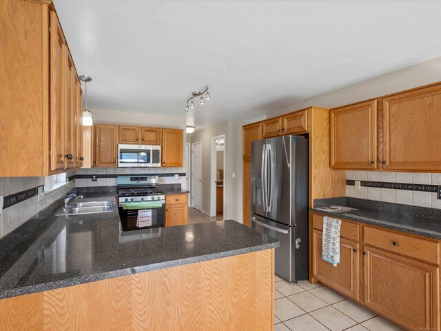 55374 Raspberry Dr, Macomb Twp, MI 48042 - kitchen featuring stainless steel appliances, a sink, decorative backsplash, light tile patterned floors, and a peninsula