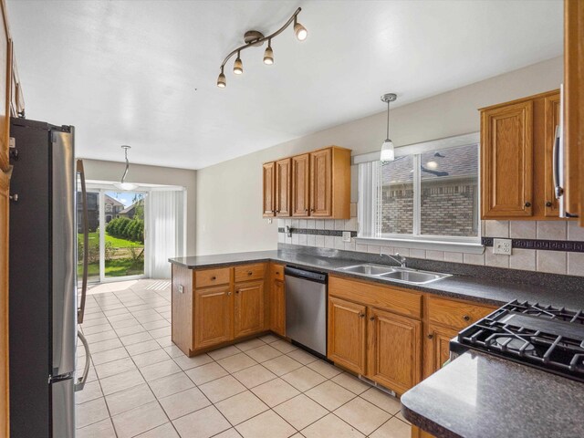 55374 Raspberry Dr, Macomb Twp, MI 48042 - kitchen featuring stainless steel appliances, a sink, dark countertops, light tile patterned flooring, and a peninsula