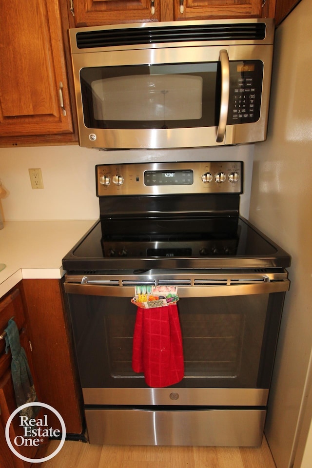 kitchen featuring stainless steel appliances, brown cabinetry, and light countertops