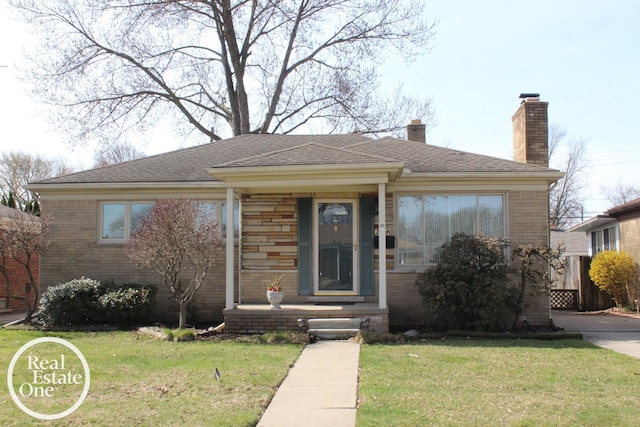 bungalow featuring a front yard, brick siding, and a chimney