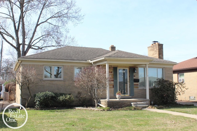 view of front of property featuring a front yard, a chimney, brick siding, and roof with shingles