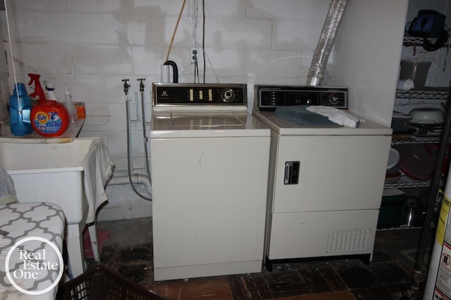 clothes washing area with separate washer and dryer and concrete block wall