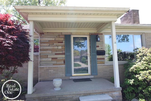 view of exterior entry with covered porch and brick siding