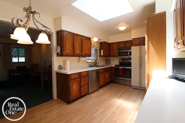 kitchen with stainless steel appliances, light wood-type flooring, a sink, light countertops, and a skylight