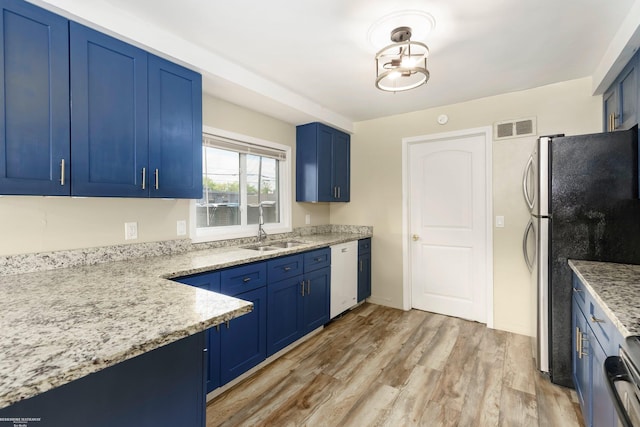 kitchen with blue cabinetry, a sink, white dishwasher, freestanding refrigerator, and light wood-style floors