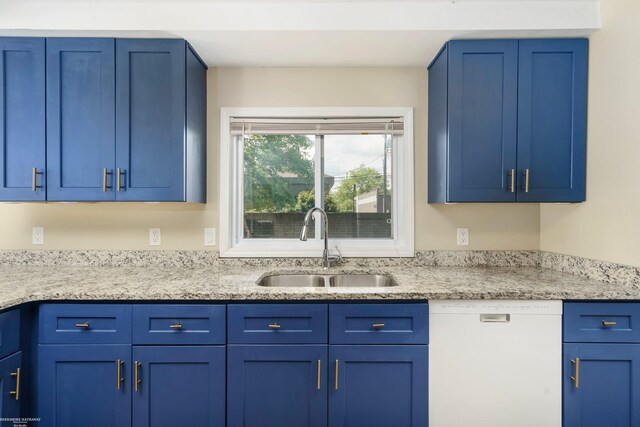 kitchen featuring dishwasher, a sink, blue cabinetry, and light stone countertops