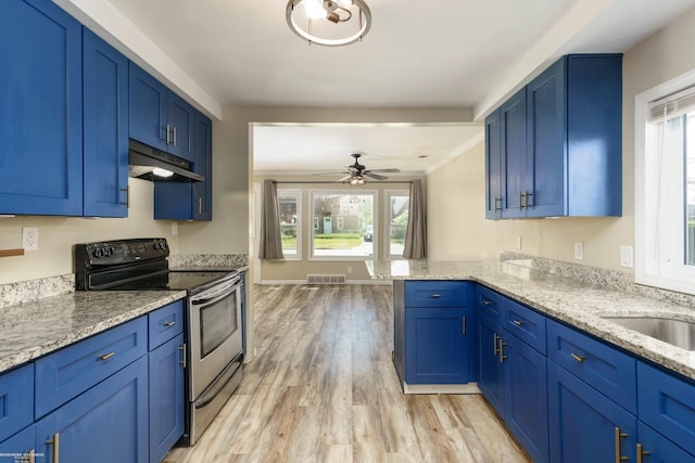 kitchen with electric range, under cabinet range hood, light wood finished floors, and healthy amount of natural light