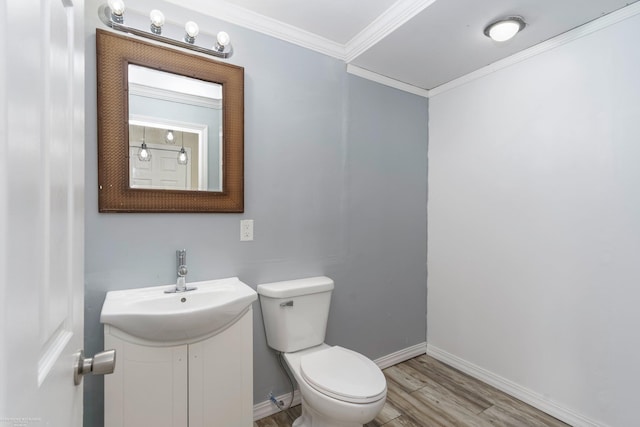 bathroom featuring wood finished floors, ornamental molding, toilet, baseboards, and vanity