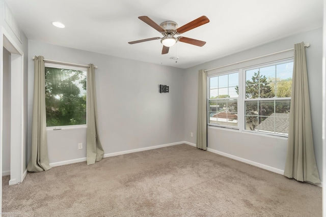 carpeted empty room with baseboards and a ceiling fan