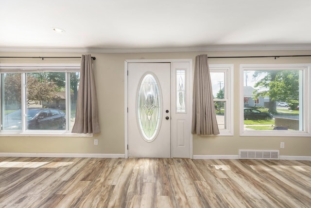 foyer with wood finished floors, baseboards, and ornamental molding