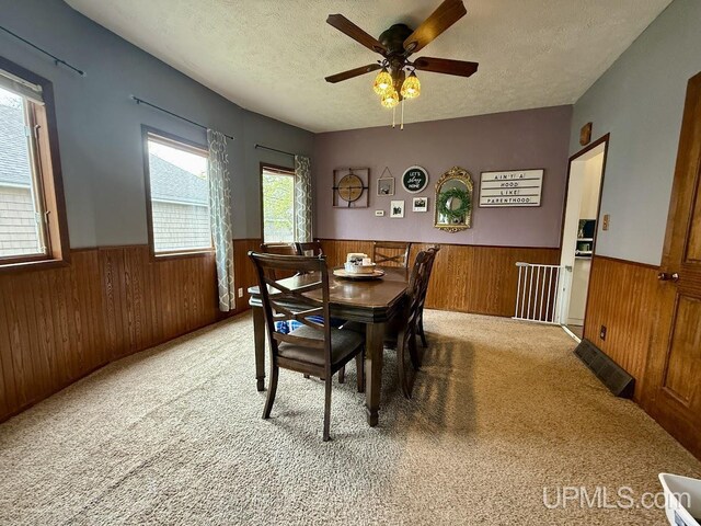 624 S 16th St, Escanaba, MI 49829 - dining space with a wainscoted wall, wood walls, a textured ceiling, carpet, and a ceiling fan
