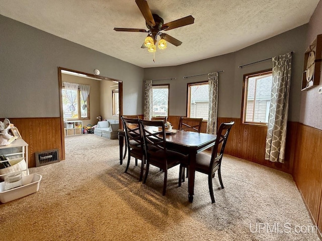 624 S 16th St, Escanaba, MI 49829 - carpeted dining area featuring a wainscoted wall, wooden walls, a textured ceiling, plenty of natural light, and ceiling fan