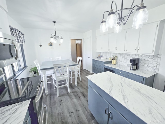 1400 W B St, Iron Mountain, MI 49801 - kitchen with a chandelier, light wood finished floors, decorative backsplash, white cabinets, and stainless steel appliances