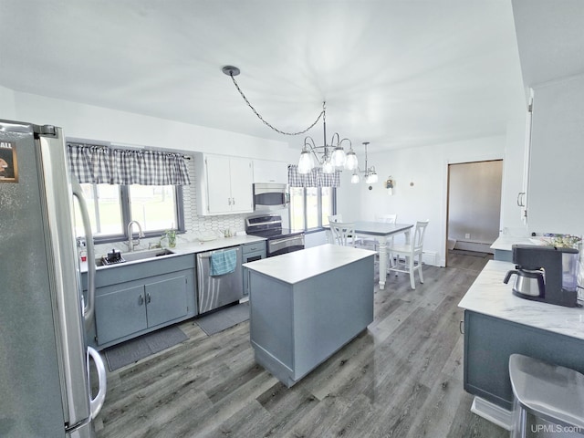 1400 W B St, Iron Mountain, MI 49801 - kitchen with appliances with stainless steel finishes, a sink, baseboard heating, a center island, and wood finished floors