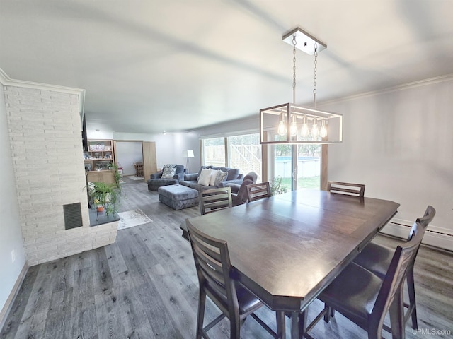 1400 W B St, Iron Mountain, MI 49801 - dining area featuring wood finished floors, a chandelier, ornamental molding, a baseboard heating unit, and baseboards