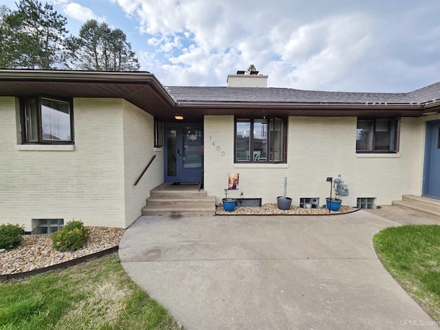 1400 W B St, Iron Mountain, MI 49801 - property entrance featuring brick siding, a chimney, and roof with shingles