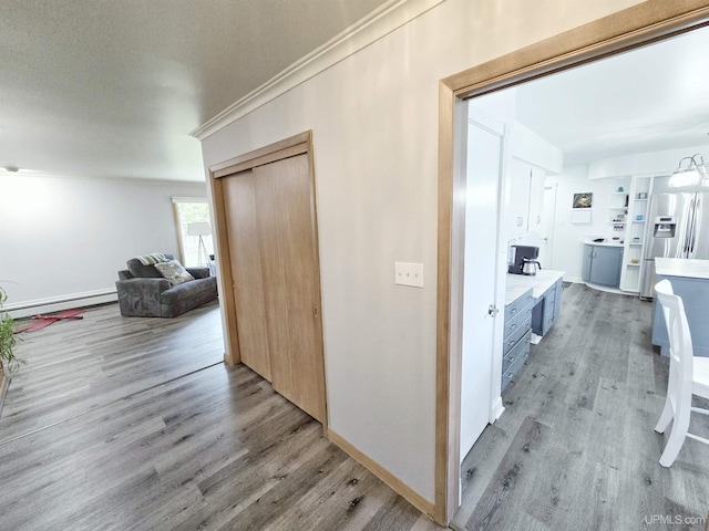 1400 W B St, Iron Mountain, MI 49801 - corridor with light wood-style flooring, a baseboard heating unit, crown molding, washer / clothes dryer, and baseboards