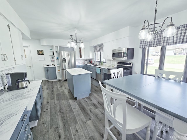 1400 W B St, Iron Mountain, MI 49801 - kitchen featuring stainless steel appliances, a chandelier, tasteful backsplash, and wood finished floors