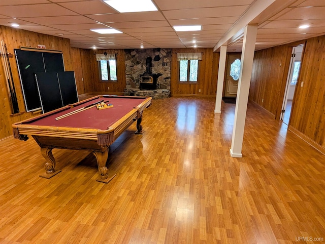 1002 Allouez Rd, Marquette, MI 49855 - playroom featuring wood walls, healthy amount of natural light, a paneled ceiling, a wood stove, and light wood-style floors