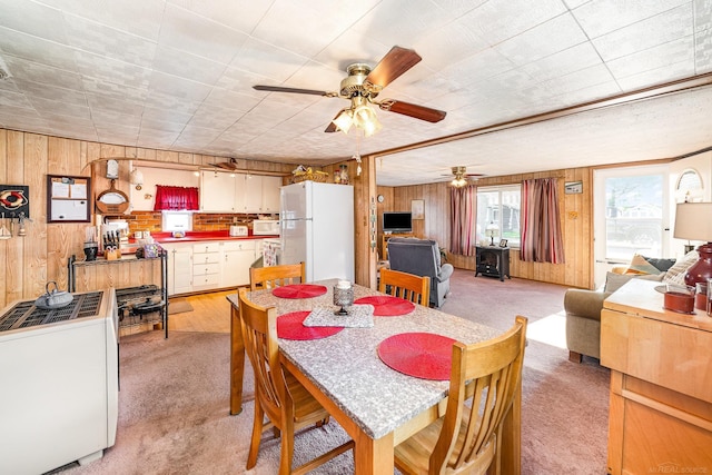 125 Wickham Ave, Houghton Lake, MI 48629 - dining area featuring light carpet, wood walls, and a ceiling fan