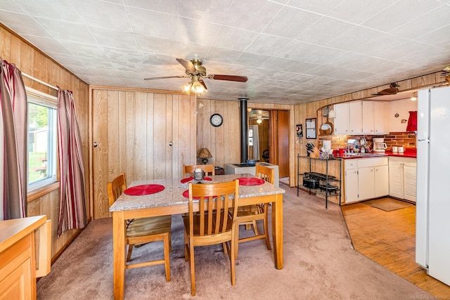 125 Wickham Ave, Houghton Lake, MI 48629 - dining area featuring wood walls, a wood stove, and ceiling fan