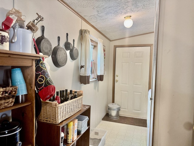foyer entrance with a textured ceiling, tile patterned floors, and ornamental molding