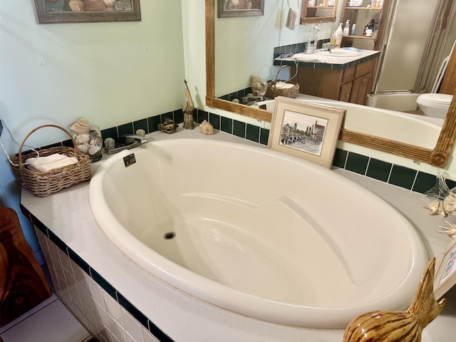 bathroom featuring a bathtub, vanity, a shower with door, and toilet