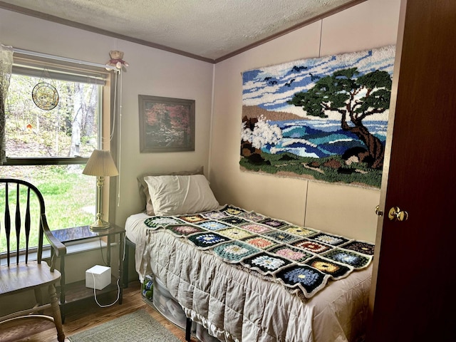 bedroom with wood finished floors, a textured ceiling, and crown molding