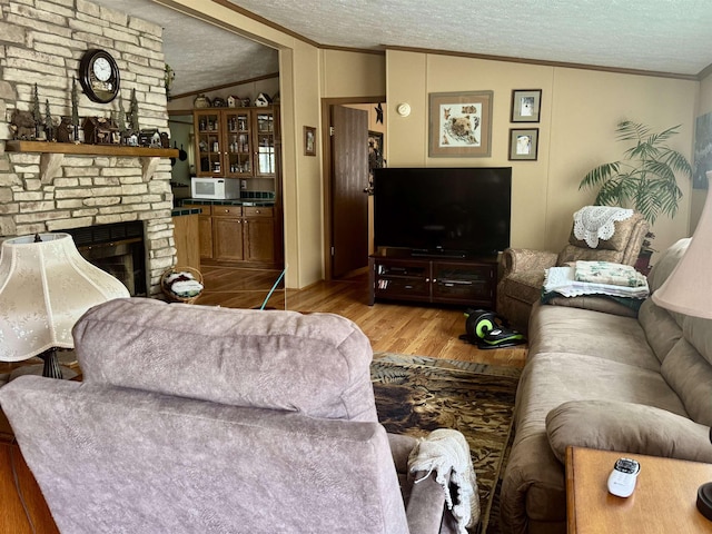 living room with crown molding, wood finished floors, a fireplace, and a textured ceiling