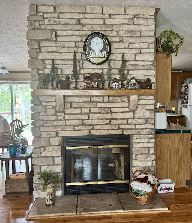 detailed view of a textured ceiling, a fireplace, and wood finished floors