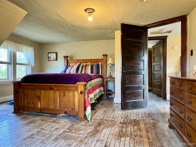 18020 Lake Rd, Pelkie, MI 49958 - bedroom featuring hardwood / wood-style floors, a textured ceiling, and baseboards