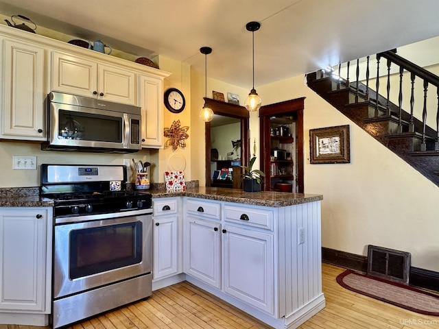 18020 Lake Rd, Pelkie, MI 49958 - kitchen with stainless steel appliances, a peninsula, light wood-style floors, pendant lighting, and white cabinetry