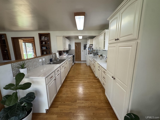 102 Forest Dr, Norway, MI 49870 - kitchen featuring a sink, light wood-type flooring, a peninsula, decorative backsplash, and stainless steel range