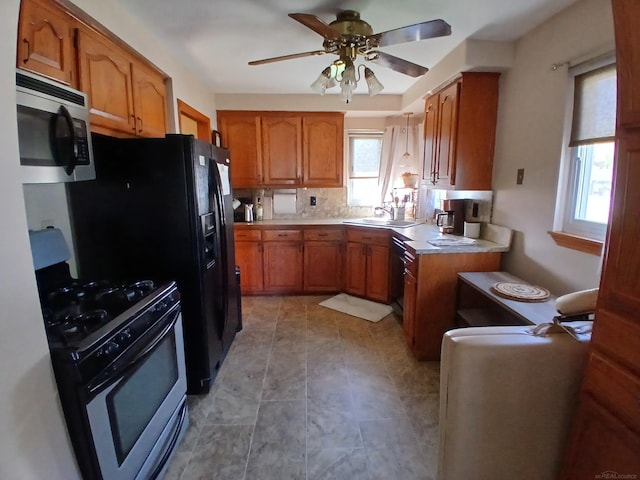 kitchen featuring stainless steel appliances, brown cabinetry, and a sink