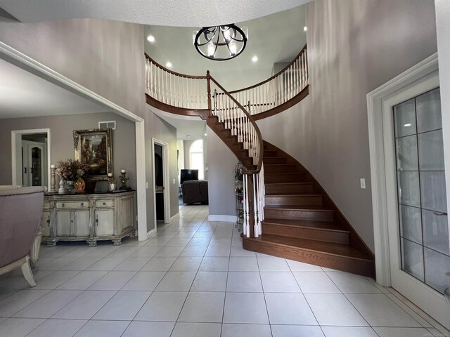 53641 Buckingham Ln, Shelby Twp, MI 48316 - foyer featuring a towering ceiling, stairs, light tile patterned flooring, and baseboards