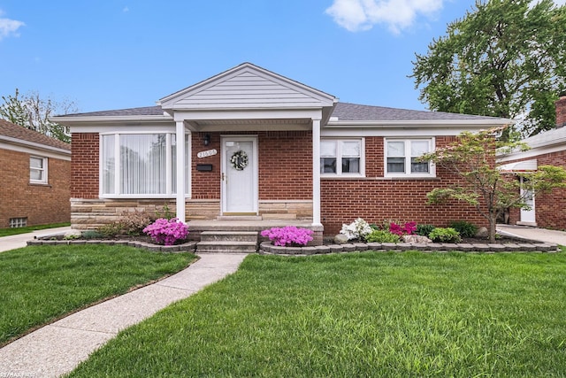bungalow with a front yard, brick siding, and roof with shingles