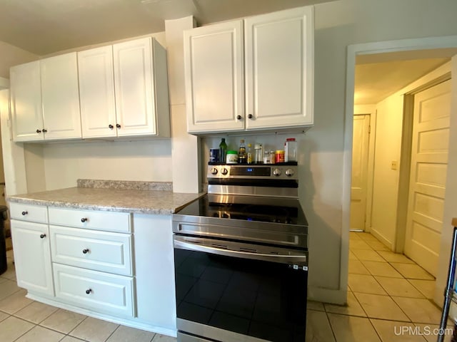 213 N Fifth St, Marquette, MI 49855 - kitchen featuring stainless steel range with electric cooktop, light tile patterned floors, white cabinets, and light countertops