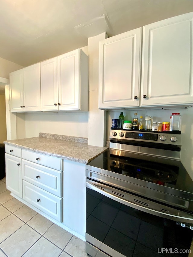 213 N Fifth St, Marquette, MI 49855 - kitchen with electric range, white cabinets, light countertops, and light tile patterned floors
